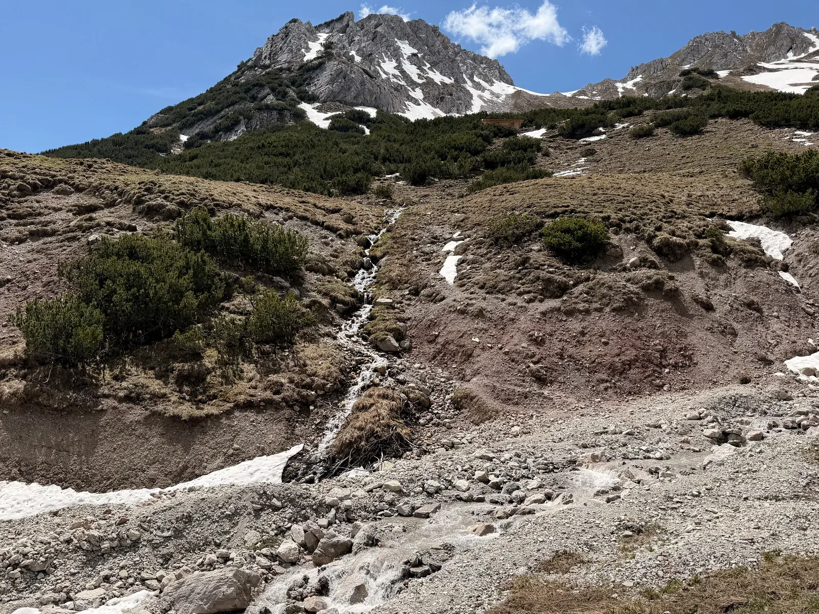 Rocky trail with snow patches below cliffs, ZUT 107K at KM 32.9.