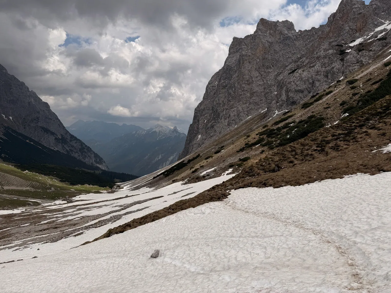 Snowfield crossing below steep rock walls, wintry conditions May 2026, ZUT 107K at KM 47.2.